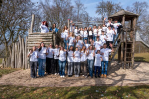 Die Wertebotschafterinnen und Wertebotschafter der oberpfälzischen Schulen stehen bei sonnigem Wetter auf und vor einem Klettergerüst.